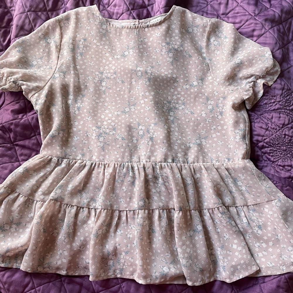 soft baby pink floral blouse, ruffles at the bottom and short sleeved.